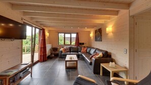 Ein geräumiges Wohnzimmer mit einem großen Sofa, einem Couchtisch und einem Flachbildfernseher.