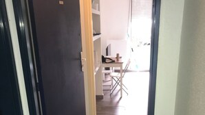 A hallway leading to a room with a dark door, a tiled floor, and a small table with chairs. - Charming studio near downtown (Strasbourg)