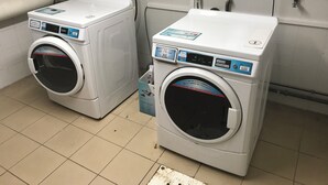 Two front-loading washing machines in a utility room with tiled walls and floor. - Charming studio near downtown (Strasbourg)