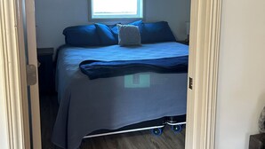 Een slaapkamer met een bed, een raam en een deur.