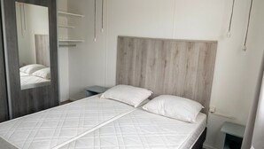 Quarto com cama, espelho e cabeceira de madeira.