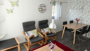 Uma sala de estar moderna com sofá, cadeiras, mesa de jantar e tapete vermelho.