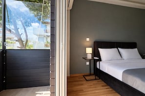 Un dormitorio con cama, mesita de noche, lámpara y vistas a través de un ventanal.