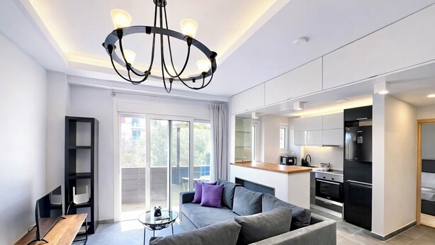A modern apartment with a living room, kitchenette, and a balcony with a view.