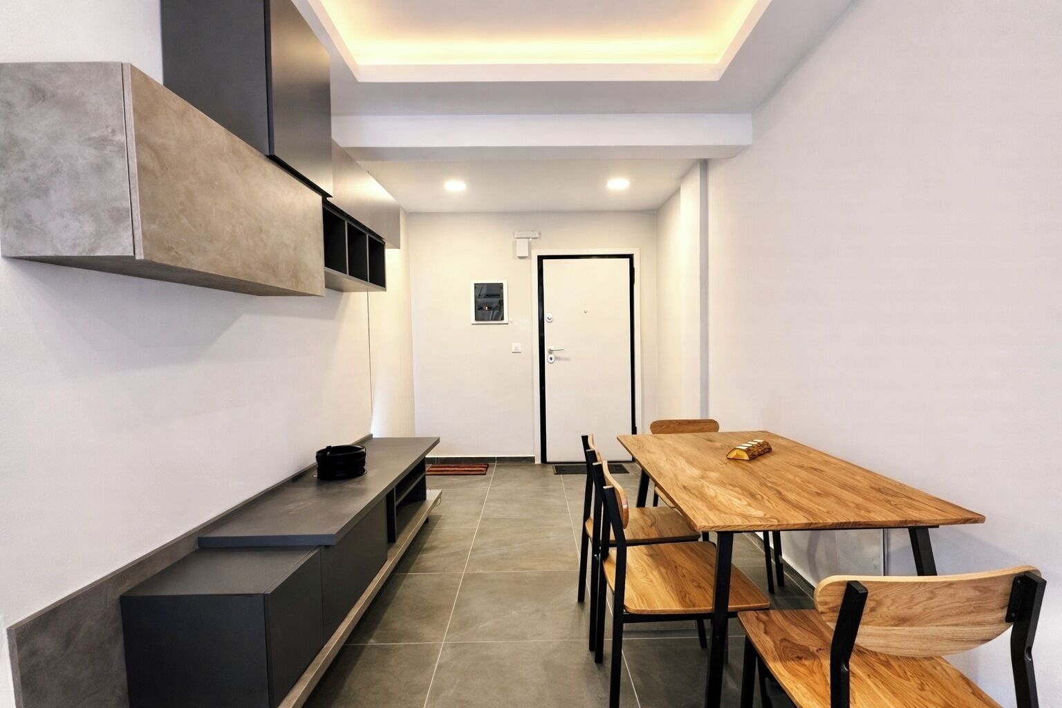 Eine moderne Küche mit integriertem Sitzplatz, einem Holztisch mit Stühlen und einer Tür im Hintergrund.