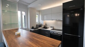 A modern kitchen with a wooden countertop, black refrigerator, and white cabinets.