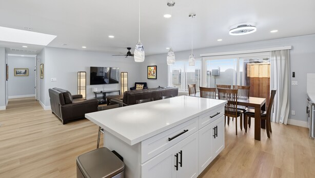 A modern kitchen with a central island, dining area with wooden chairs, and a living room with a sofa and TV. - Modern 4BR Home, Sleeps 9, Near Silicon Valley (San Jose)