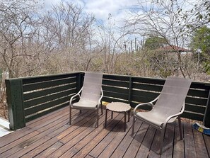 A wooden deck with two metal chairs and a small round table. - Alablanka - The green flamingo (Sint Willibrordus)