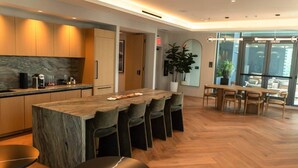 Cozinha moderna com uma ilha grande, sala de jantar com cadeiras de madeira e uma janela ampla que traz luz natural.