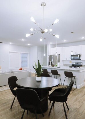 A modern kitchen with a central island, a dining area with a round table and chairs, and a ceiling light fixture. - Down-Town/ Alamo dome/tower of americas/ hemisphere park (San Antonio)