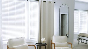 A modern room with two white armchairs, a small round table with a vase, and a bed with a headboard. - Down-Town/ Alamo dome/tower of americas/ hemisphere park (San Antonio)