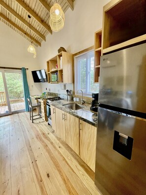 A modern kitchen with wooden cabinets, a stainless steel refrigerator, and a built-in oven.
