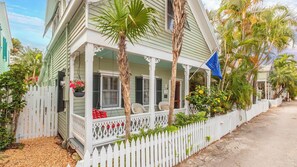 A house with a porch, white picket fence, and tropical plants. - Pineapple Conch House (Key West)