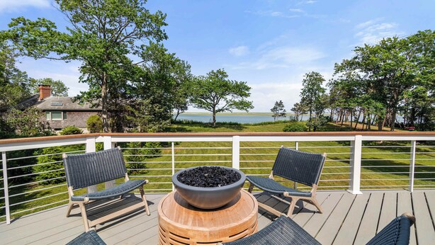 Une terrasse avec deux chaises, un foyer extérieur et une vue sur un lac.
