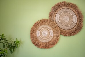 Two circular woven wall hangings with fringe edges on a light green wall. - Saffraanvink - The green flamingo (Sint Willibrordus)