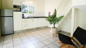 Eine moderne Küche mit weißen Schränken, einem Edelstahl-Kühlschrank, einer Mikrowelle und einem Blumentopf.
