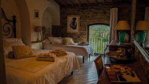 A bedroom with two beds, a wooden floor, a stone wall, a balcony with a view, and a table with a tray. - Villa La Serra-View and Charm in Tuscany (Toscana)