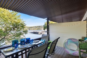 An outdoor dining area with a view of a body of water, a covered seating area, and a floating ring. - Lakefront Bungalow Near Margaritaville (Osage Beach)