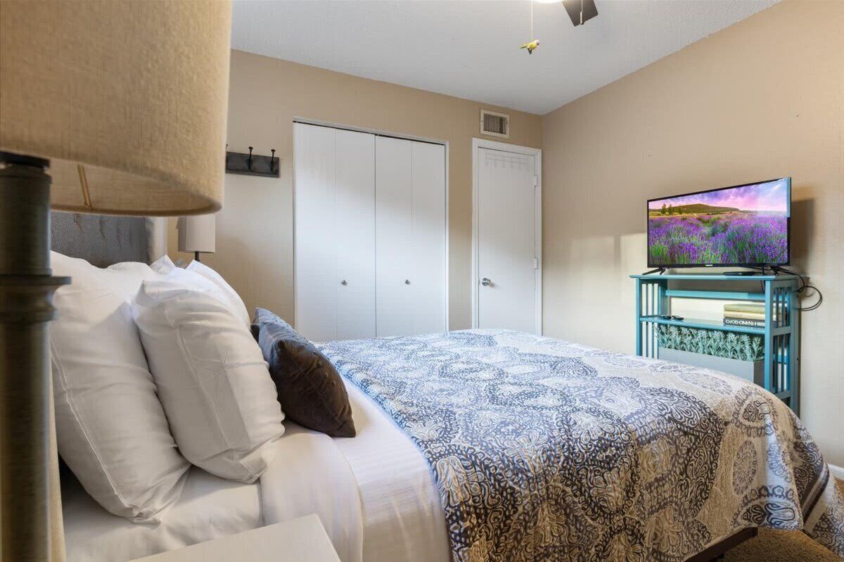 Une chambre à coucher avec un lit, un téléviseur posé sur un meuble et une armoire.