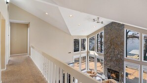 A spacious interior with a high ceiling, a stone fireplace, and large windows offering a view of the outdoors. - Lakefront House, Dock, Fire pit (Sunrise Beach)