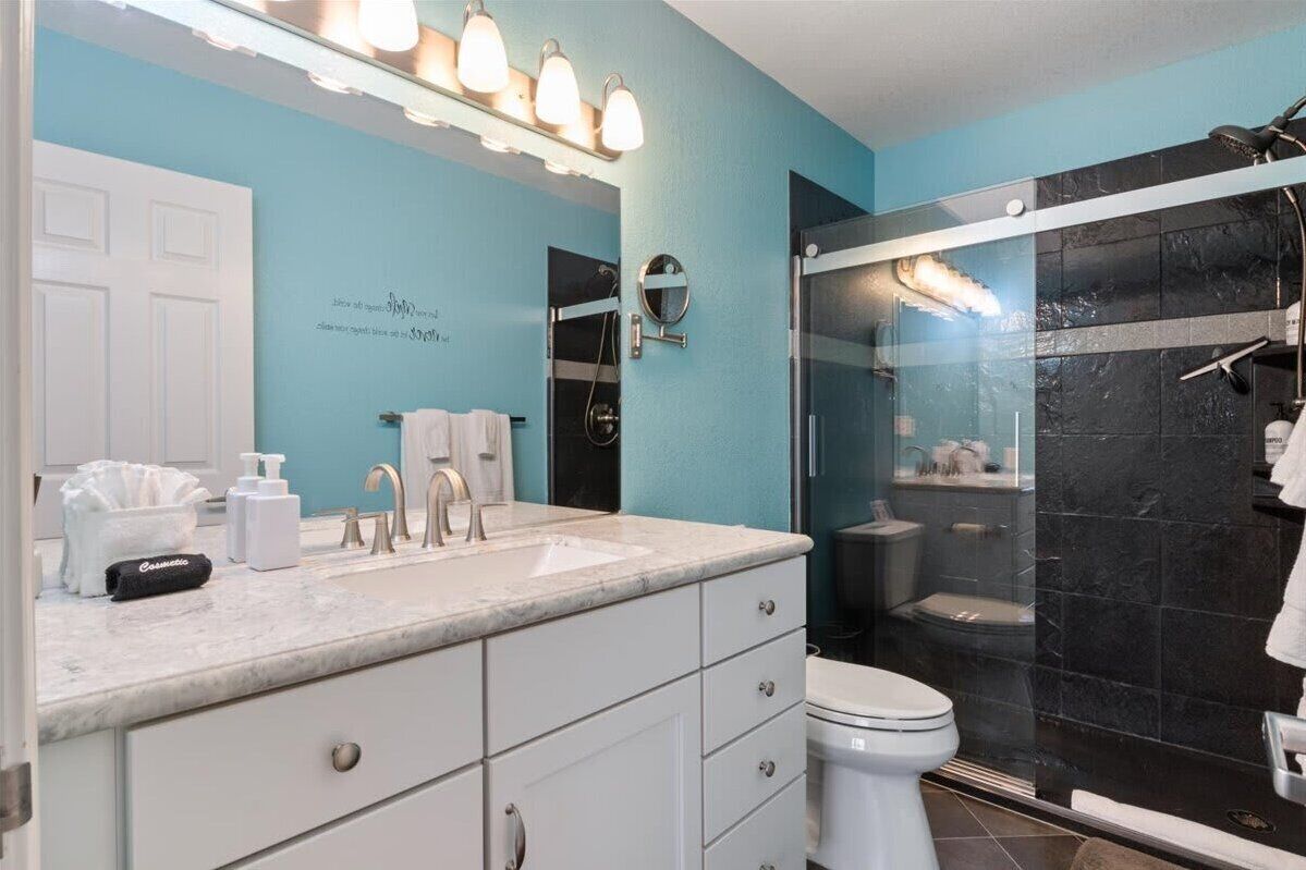 A bathroom with a blue wall, white vanity, and a glass-enclosed shower.
