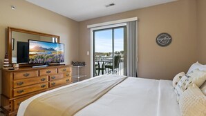 Een hotelkamer met een groot bed, een houten dressoir, een flatscreen televisie en een balkon met uitzicht.
