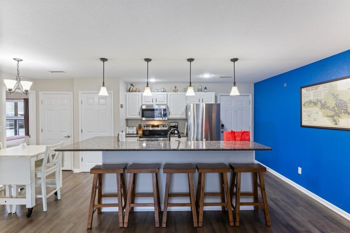 Uma cozinha moderna com armários brancos, eletrodomésticos de aço inoxidável e uma parede azul de destaque.
