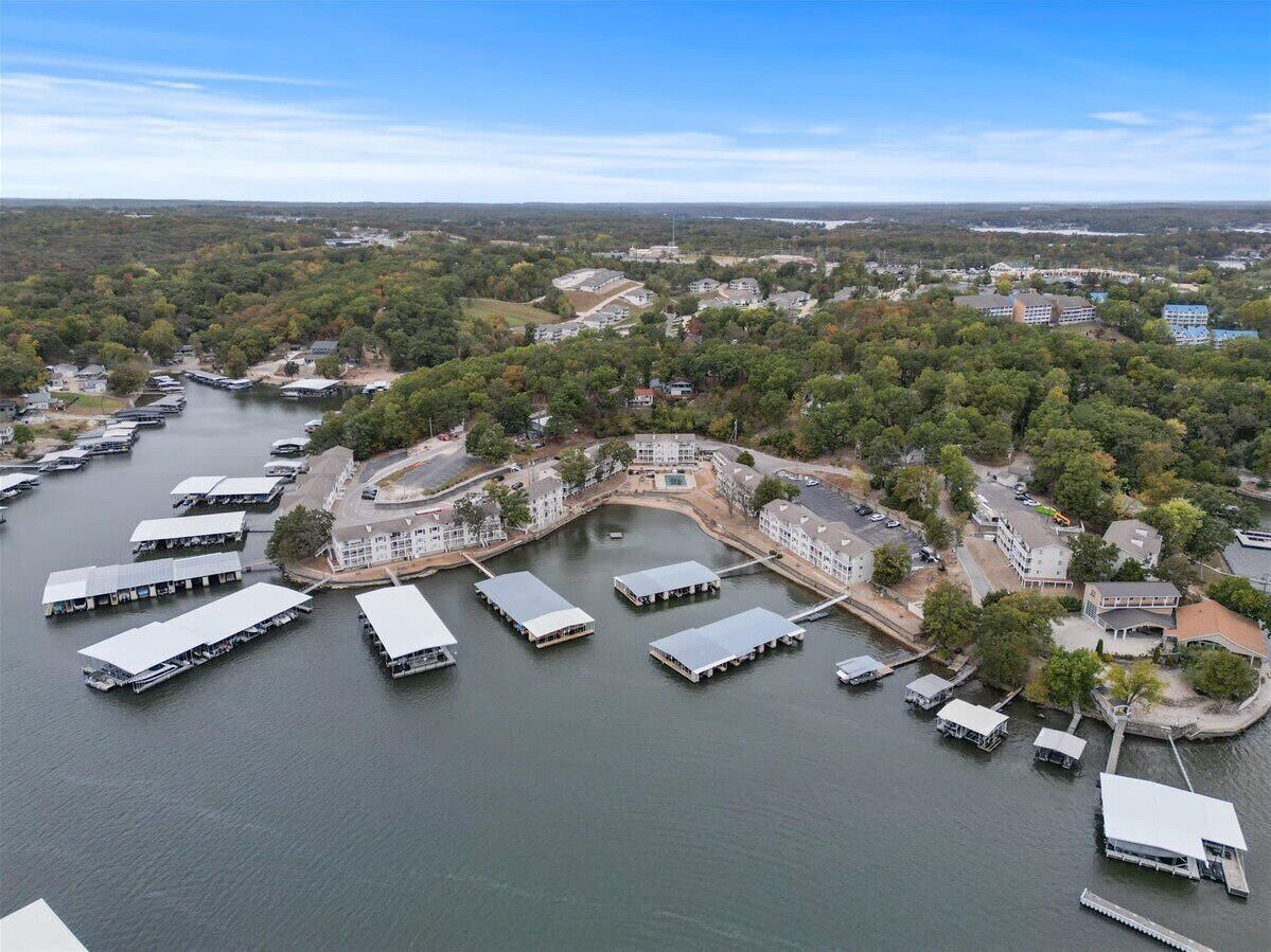 An aerial view of a marina with multiple docked boats, surrounded by residential buildings and greenery.