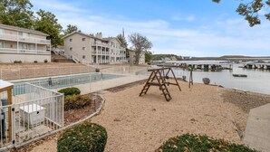 Een strandhotel met een zwembad, een schommel en een steiger die in het water uitloopt.