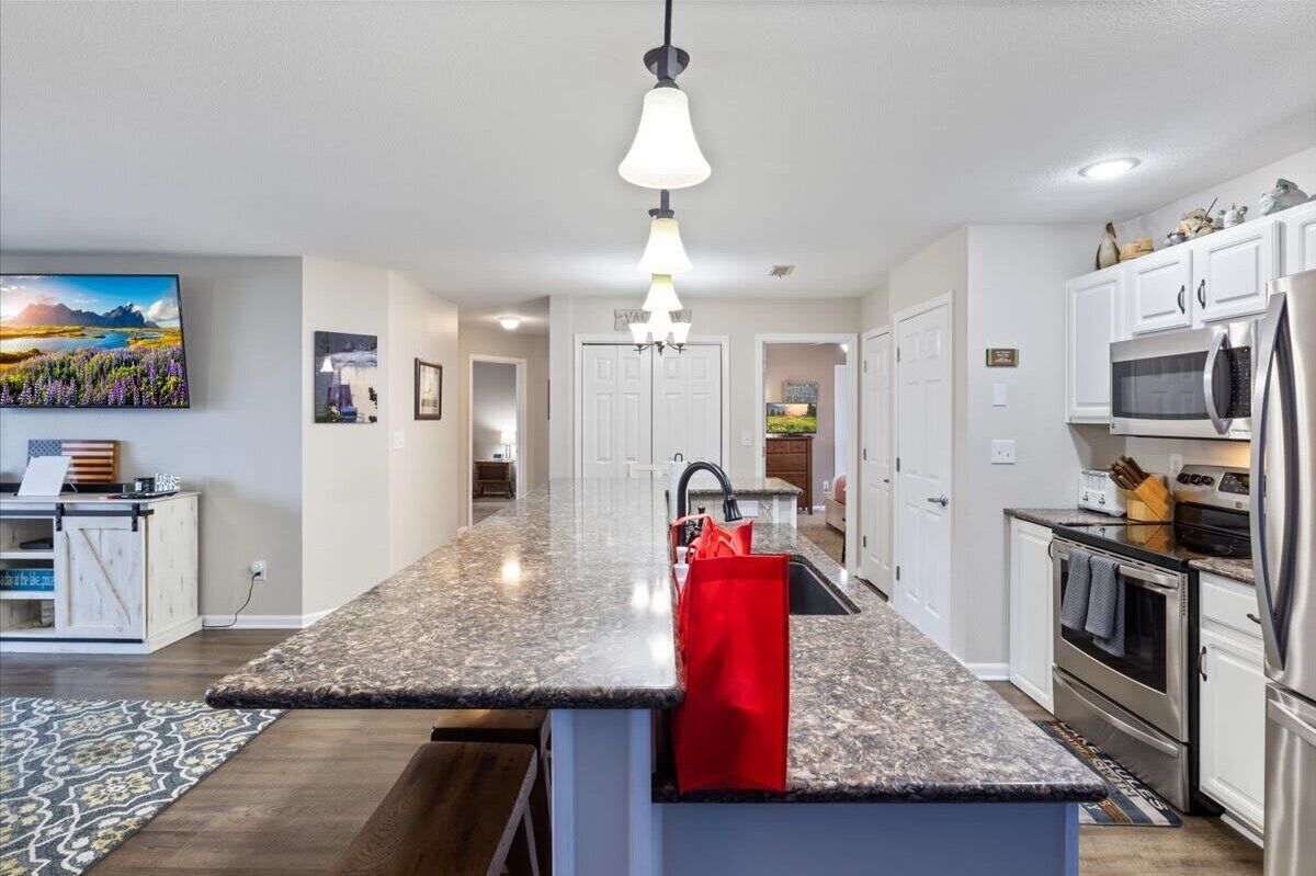 A modern kitchen with granite countertops, stainless steel appliances, and a central island with a red towel.