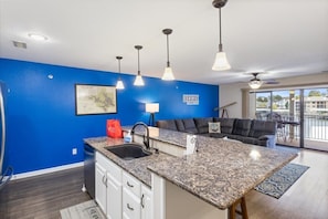 A kitchen with blue walls, a granite countertop, a sink, and overhead lighting. - Lakefront Condo With Boat Slip (Osage Beach)