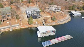 Une propriété au bord du lac, comprenant une grande maison, un quai et un bateau.