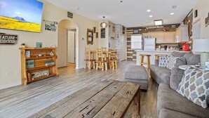 A spacious living area with a wooden coffee table, a gray sofa with patterned cushions, and a dining area with wooden chairs. - Main Channel View, Playground, no Steps Enrty (Lake Ozark)