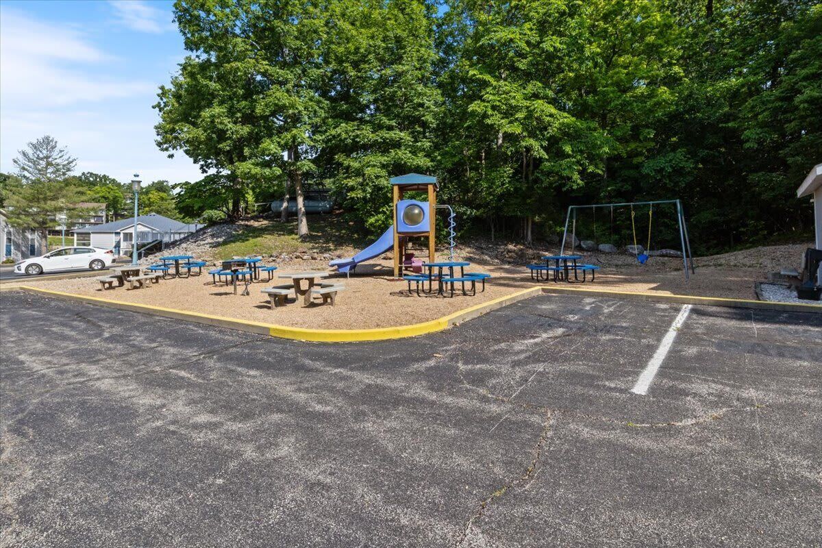 A playground with a slide, swings, and picnic tables.