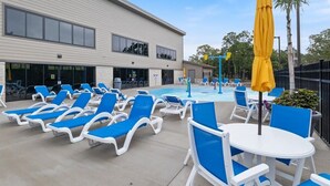 A pool area with blue lounge chairs and a yellow umbrella, a building with large windows, and a fenced area with trees. - Main Channel View, Playground, no Steps Enrty (Lake Ozark)