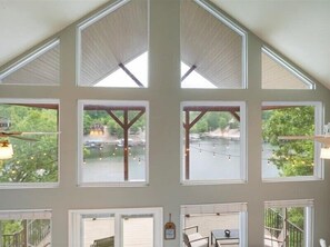 A room with multiple windows, each with a view of a body of water and greenery. - Lakefront Home With Private Dock (Eldon)