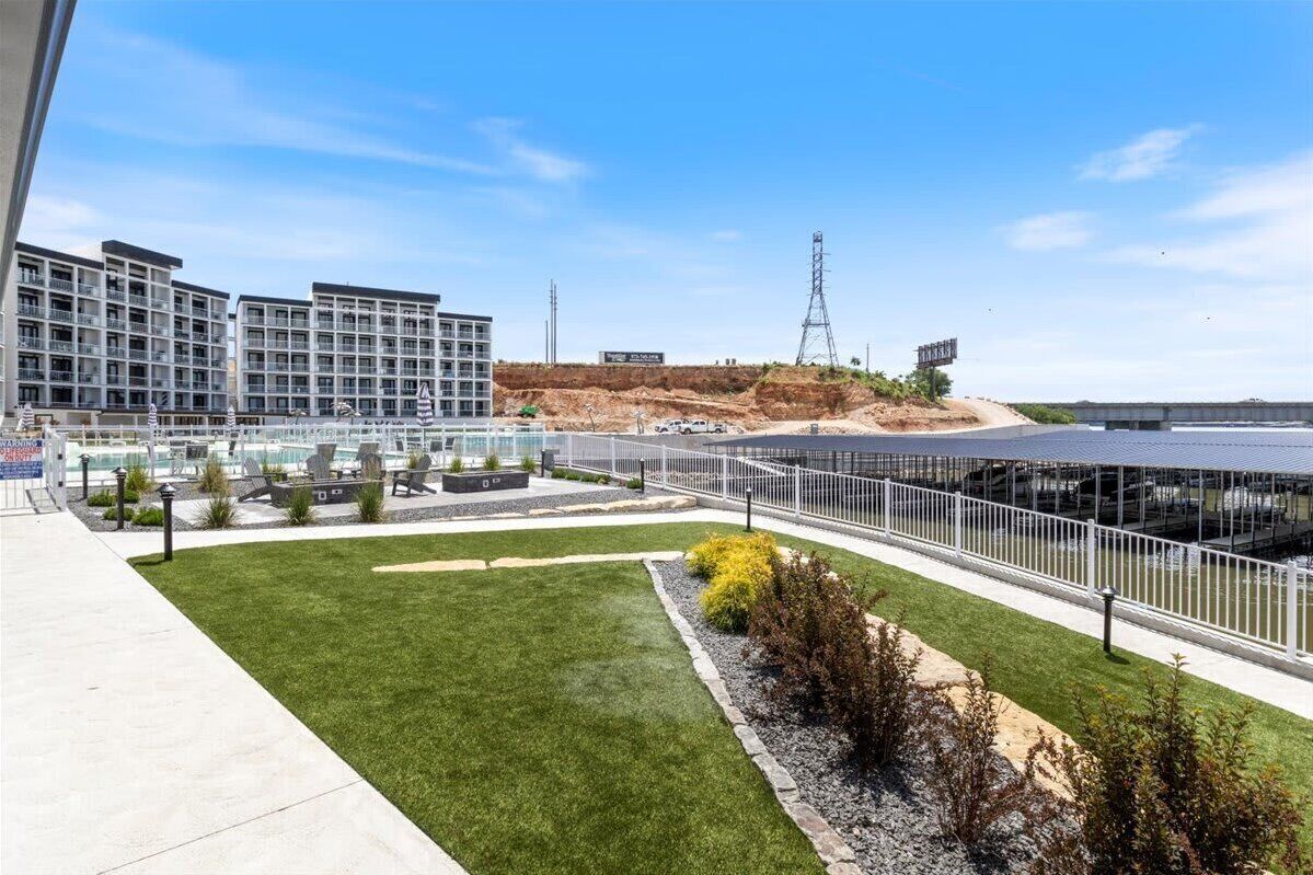 Et moderne hotel med flere etager, en anlagt gårdsplads og udsigt til en byggeplads i baggrunden.