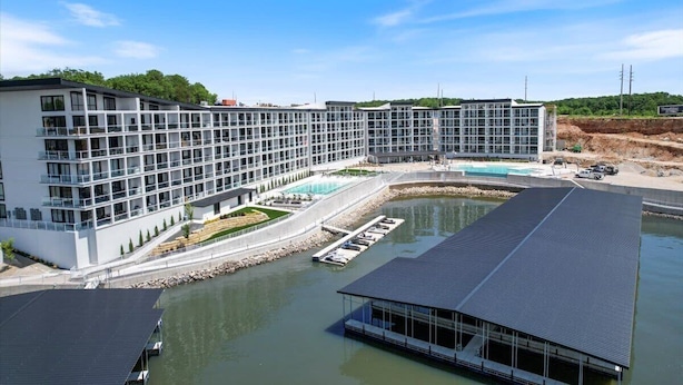 A modern hotel with a large pool, a covered outdoor area, and a waterfront view. - New Topsider Condo With Boat Slip (Osage Beach)