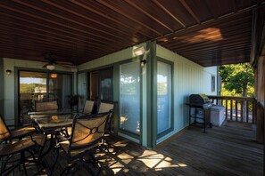 An outdoor patio with a glass table and chairs, a ceiling fan, and a grill. - Lakefront Condo With Indoor Pool (Lake Ozark)