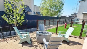 An outdoor patio with a fire pit, lounge chairs, and a fenced yard. - The Nest @ Dovetail Cozy Condo in the Hill Country (New Braunfels)