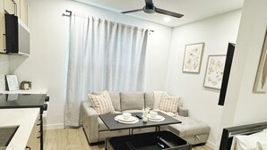 A modern living room with a sofa, coffee table, and a dining area. - The Nest @ Dovetail Cozy Condo in the Hill Country (New Braunfels)