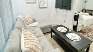A modern living room with a grey sofa, a coffee table, a ceiling fan, and two framed floral artworks. - The Nest @ Dovetail Cozy Condo in the Hill Country (New Braunfels)