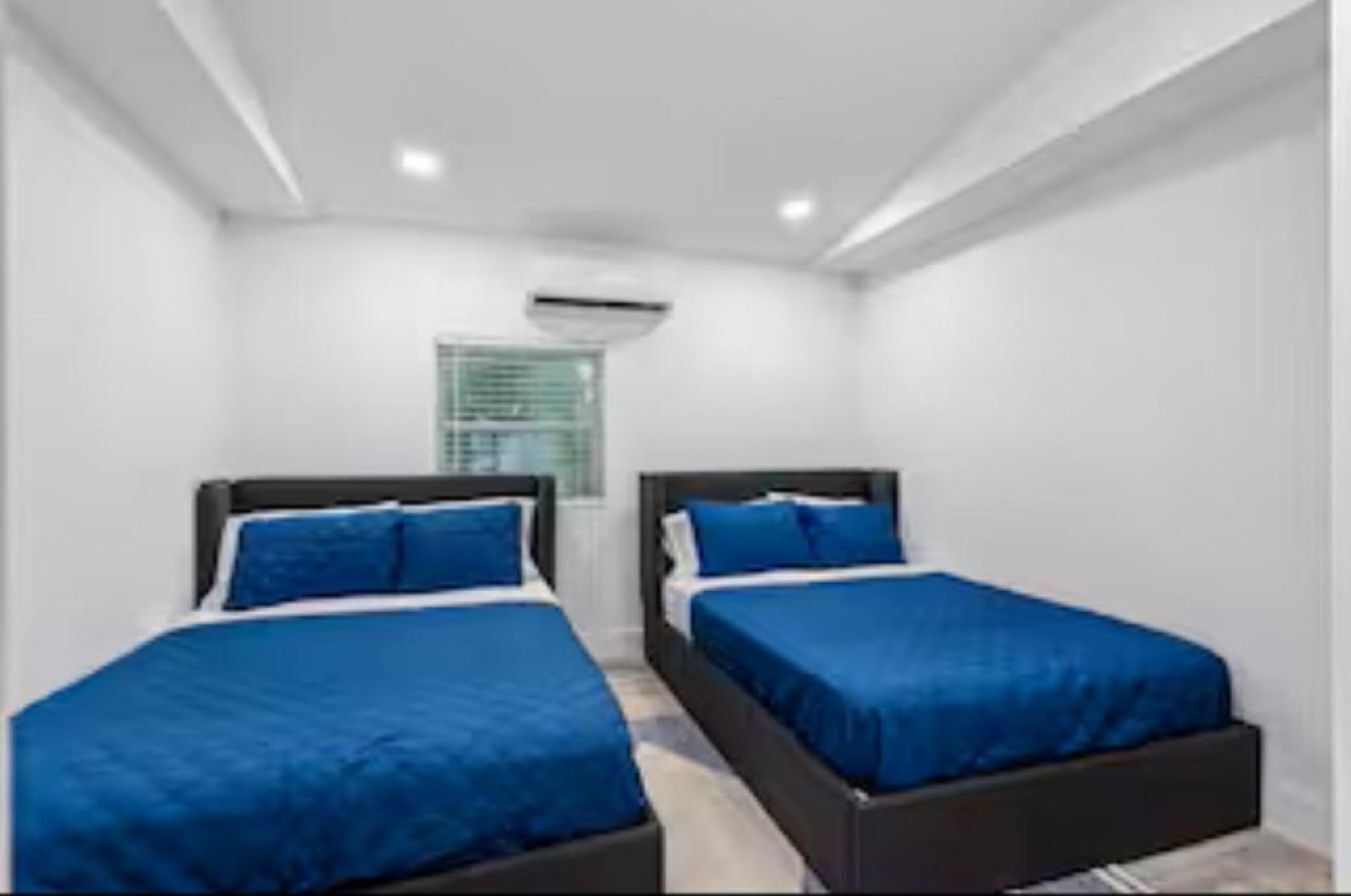 A room with two beds, white walls, and a window with blinds.