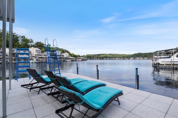 A waterfront pool area with lounge chairs and a blue pool ladder. - Beautiful Lake Front Home With Private Dock In Lick Branch Cove (Rocky Mount)