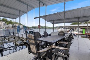 An outdoor seating area with a view of the water, a covered patio, and a 'NO FIREWORKS' sign. - Beautiful Lake Front Home With Private Dock In Lick Branch Cove (Rocky Mount)