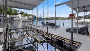 A covered dock area with a 'NO FIREWORKS' sign, watercraft, and chairs. - Beautiful Lake Front Home With Private Dock In Lick Branch Cove (Rocky Mount)