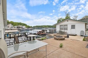 A patio area with a table and chairs, a small fire pit, and a view of a marina with boats and docked houses. - Beautiful Lake Front Home With Private Dock In Lick Branch Cove (Rocky Mount)