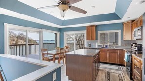 A modern kitchen with a large island, wooden cabinets, and a view of the outdoors. - Sleeps 26 Lakefront w/ Private Dock & Dance Floor! (Lake Ozark)