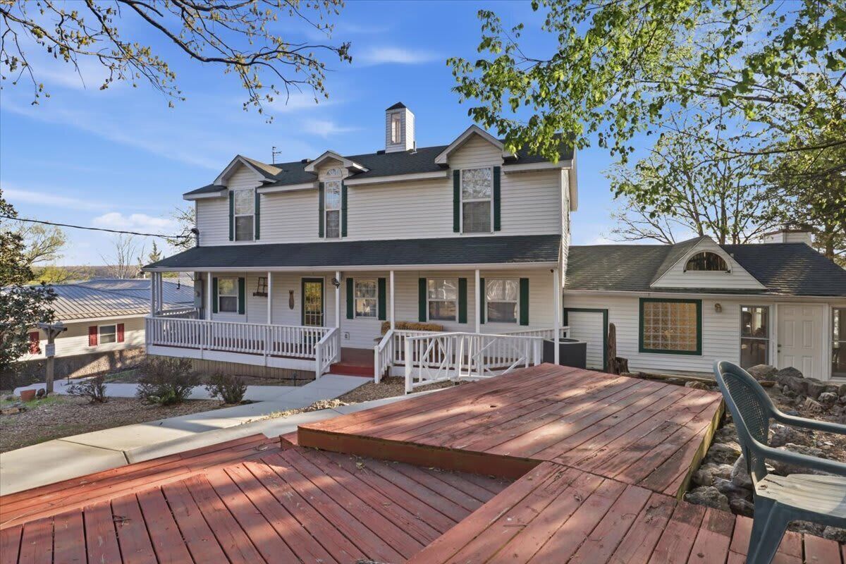 A two-story house with a front porch, a deck, and a small attached garage.