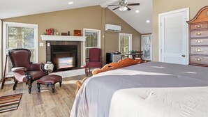 A bedroom with a large bed, a fireplace, a ceiling fan, and a dresser. - Lakeview Manor With Historic Charm and Serene Waters (Osage Beach)